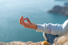 Yoga, Gesture And Healthy Lifestyle Concept - Hand Of Meditating Yogi Woman Showing Gyan Mudra Over Sea Sunset Background