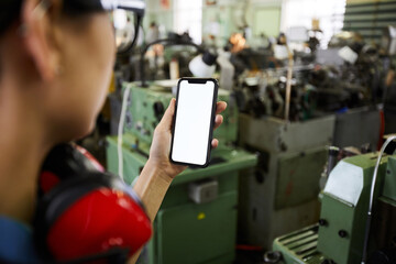 Wall Mural - Close-up of engineer woman using smartphone while photographing workplace of factory shop