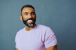 © Carlos David - headshot of a handsome smiling african american man with beard and mustache purple shirt on a gray background looking away at copy space studio