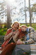 © chika_milan - A grandmother is laughing and having fun with her adolescent granddaughter while sitting on the park bench.