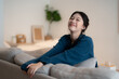 Teenager Asian woman feeling happy smiling and looking to camera while relax in living room at home.