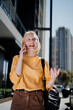 © Jelena - Happy girl walking on the street using the phone. Beautiful blonde girl talking to the smartphone.