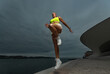 © Mike Orlov - Woman in fitness wear doing jumping workout outdoors.. Sporty gitl with fit body in sportswear posing on sky background.