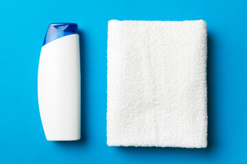 Cosmetic shampoo bottle mockup with towels on a colored table. Bathroom background, toilet accessories for hand and body care