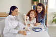 © Studio Romantic - Little cute girl examines anatomical model of spine who is standing on table in doctor's office. Female physiotherapist explains structure of spine to curious little girl and her smiling mother.