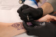 © New Africa - Professional artist making tattoo on hand at table, closeup