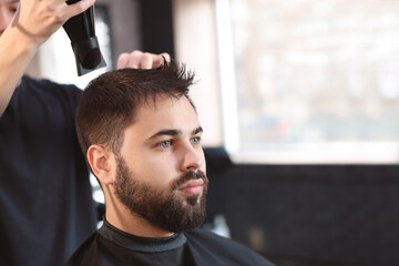 Professional hairdresser working with client in barbershop