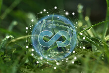 Circular Economy Concept. Green Grass With Dew And Illustration Of Infinity Symbol In Earth