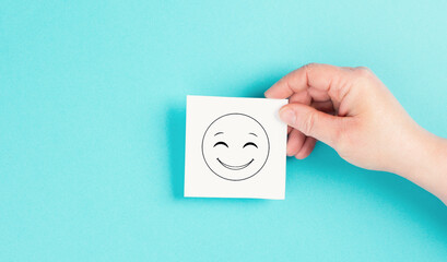 Wall Mural - Smiling happy face on a paper, positive emotions, good customer feedback, laughing, blue background
