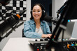 © Drobot Dean - Beautiful happy young female radio host using microphone and laptop while broadcasting in studio