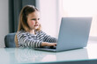© F8  \ Suport Ukraine - Cute little girl smiling and looking at laptop. Little girl using laptop
