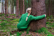 ©  sailka - Woman sitting in forest hugging tree, enjoys the silence and beauty of nature.