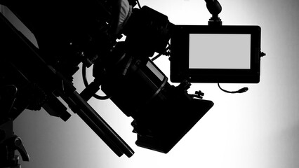 Silhouette images of video camera in tv commercial studio production which operating or shooting by cameraman and film crew team in set and prop on professional crane and tripod for easy to pan tilt o