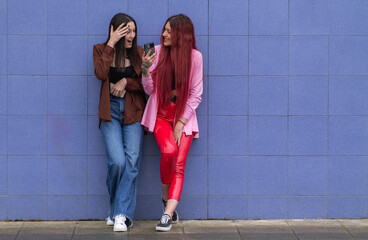 Wall Mural - young friends with surprise gesture looking at the mobile phone in the street