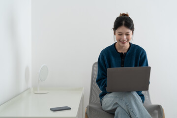 Wall Mural - Happy smiling woman sitting on sofa, couch and using laptop at living room at home, watching funny video, learning language, video calling, mother working online