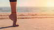 foot on tiptoe in balance on sand of beach with sun rays