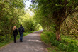 © mark_gusev - Couple walking in a forest park on a small foot path. Back to camera. Romantic time on open air. Spending time together.