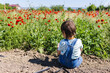 © Olga - Toddler boy playing with solid in front of poppy field. Lifestyle concept.
