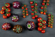 Assortment of different kinds of tomatoes and cherry tomatoes on black background, top view. 