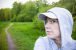 Woman in hood and cap in park among trees