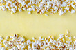 Popcorn background. Air corn frame. Opened corn grains on a yellow background with copy space.
