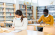 © JackF - Portrait of young adult woman wearing mask for viral protection studying in at public library