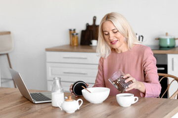 Wall Mural - Morning of mature woman having breakfast in kitchen