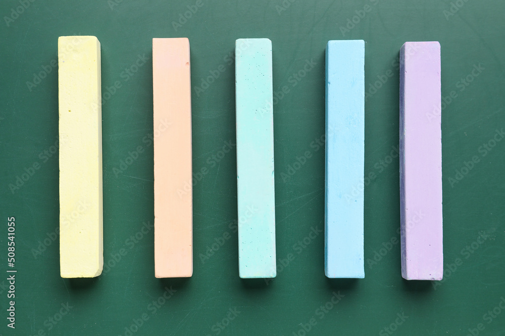 Colorful chalks on green blackboard, top view