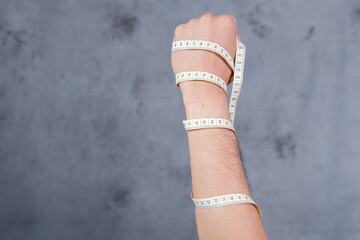 Wall Mural - Close-up of a man's hand wrapped in measuring tape. Healthy lifestyle. Diet problem.