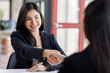 © David - Pretty Young Asian business woman shaking hands with business in her office during a meeting