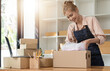© Natee Meepian - Asian female online store small business owner seller entrepreneur packing package post shipping box preparing delivery parcel on table. Ecommerce dropshipping shipment service concept.