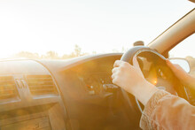 Golden Sunlight Flare Over Steering Wheel And Hands Of Car Driver