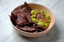 Close Up Shot Of Guacamole With Chocolate Flavoured Taco Chips In A Pink Bowl