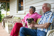 © Austockphoto - Old couple sitting on the front porch with their pet dog