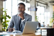 © Mediaphotos - Serious handsome young black businessman in stylish suit sitting at table with diary and laptop and looking at camera in restaurant
