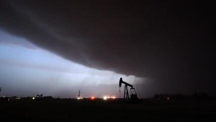 Wall Mural - Silhouette of pumpjack in oil field as dangerous thunderstorm rolls in through West Texas as lighting flashes.