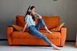 © SHOTPRIME STUDIO - portrait of a woman listening to music with headphones on the orange sofa Lifestyle