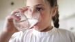 © ibragimova - child girl drinking water from a glass cup. the problem of lack of clean drinking water in the world. little girl in the kitchen drinks drinking water from a lifestyle transparent glass cup