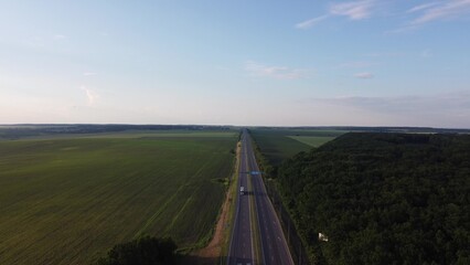 Aerial View Cargo Truck. Large Delivery Truck is Moving. Aerial Shot Of Lorry On Road In Beautiful Countryside. Aerial View of Semi-truck on Road In Spring Day Field