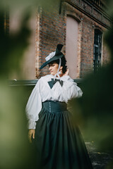 Portrait of beautiful woman in green vintage hat 1800s early 1900s clothing.