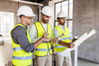 © Syda Productions - architecture, construction business and people concept - male architects in helmets with clipboard discussing blueprint in office building