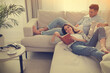 © New Africa - Happy couple with book on sofa in living room