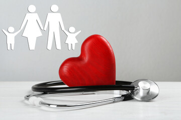  Health insurance. Stethoscope, red heart on white wooden table and illustration of family