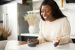© Vadim Pastuh - Charming young African-American young woman is using voice commands for wireless smart speaker control. Smart home and technology concept
