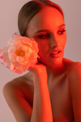 Wall Mural - Beautiful young woman with white pink flower on orange neon light background