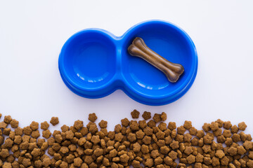 Wall Mural - top view of bone shaped dog treat in blue bowl near pet food.