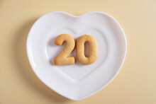 Biscuits Forming Number 20 On The White Plate And Yellow Light Background