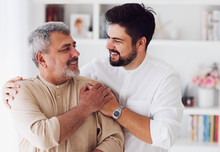 Portrait Of Cheerful Laughing Adult Father And Son At Home