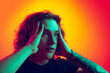 © master1305 - Young shocked man with long curly hair posing isolated on gradient orange-pink background in neon. Concept of beauty, fashion, youth culture and emotions