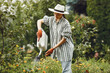 Women pours flowers in the garden with watering can